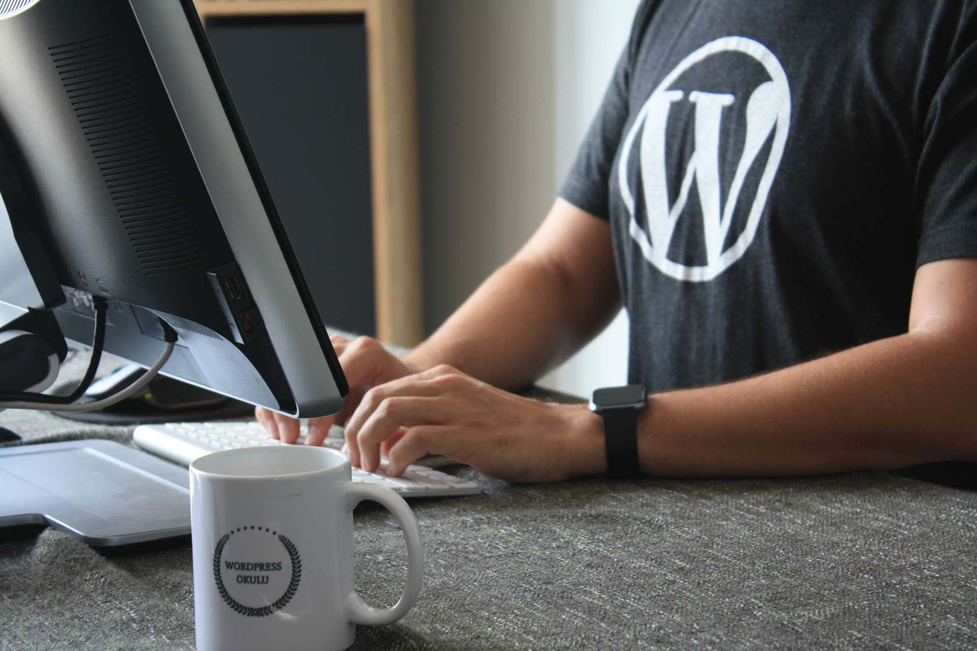 homme devant un ordinateur avec un t-shirt au logo Wordpress